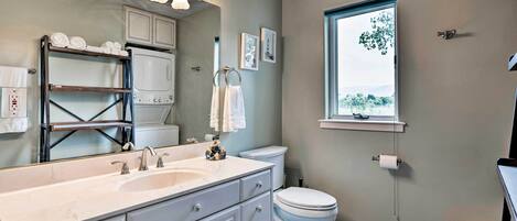 A bathroom with a large sink, toilet, and a window with a view.