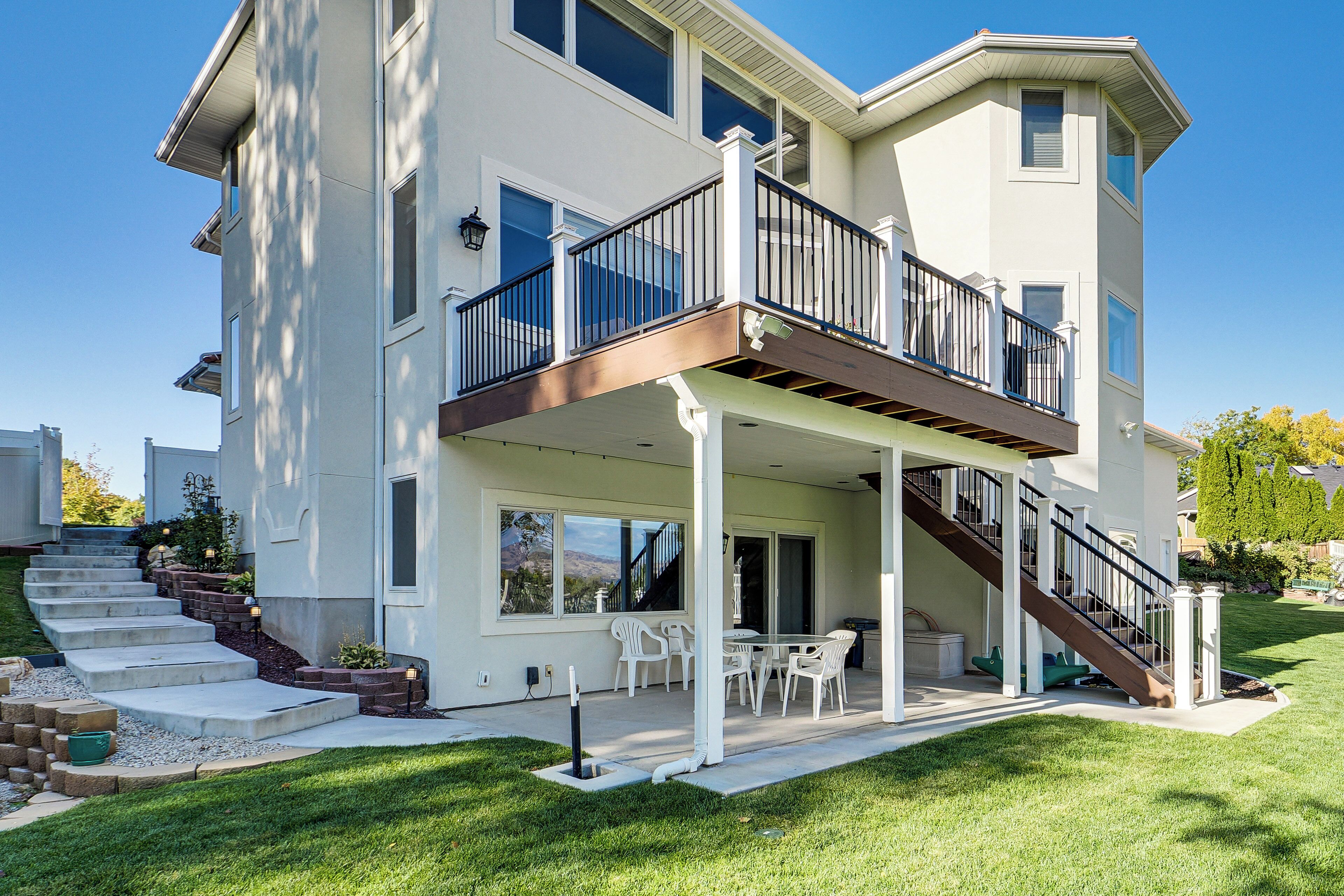 A two-story house with a covered patio, outdoor seating, and a staircase leading to the upper level.