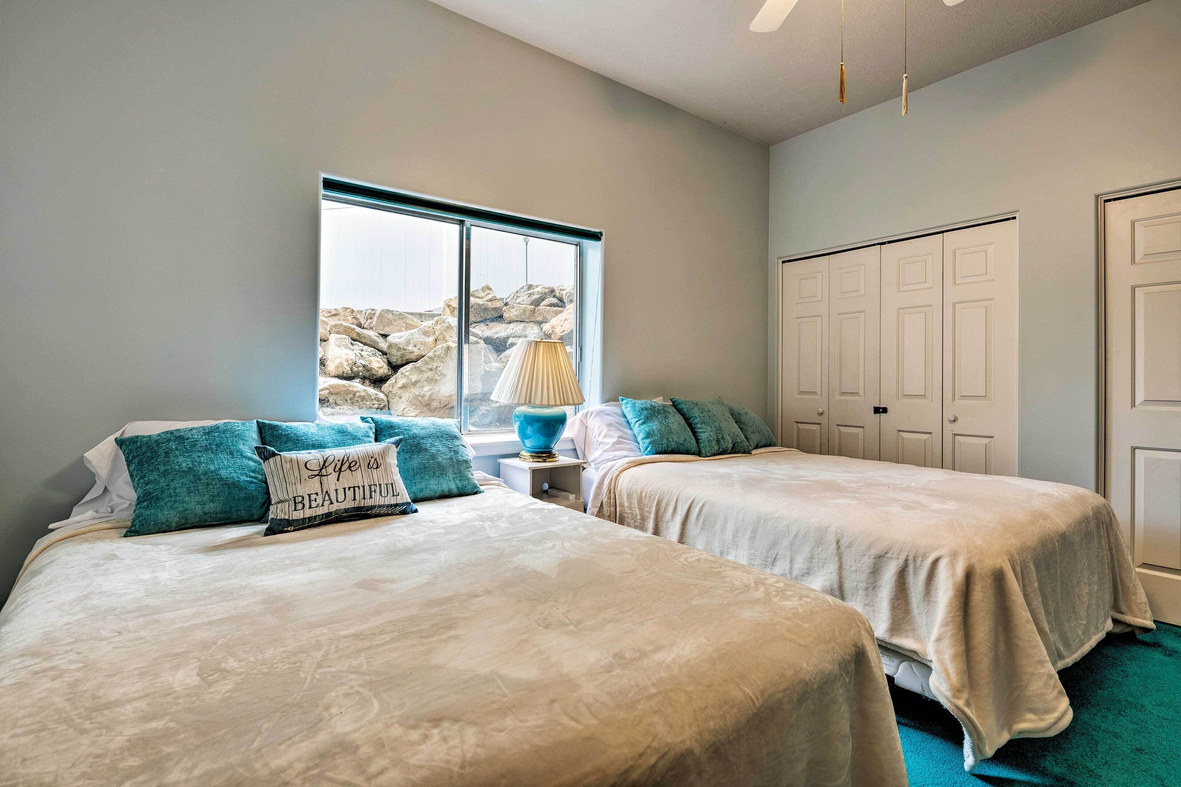 Ein Schlafzimmer mit zwei Betten, einem Fenster mit Blick auf Felsen, einer Lampe und einem Kleiderschrank.