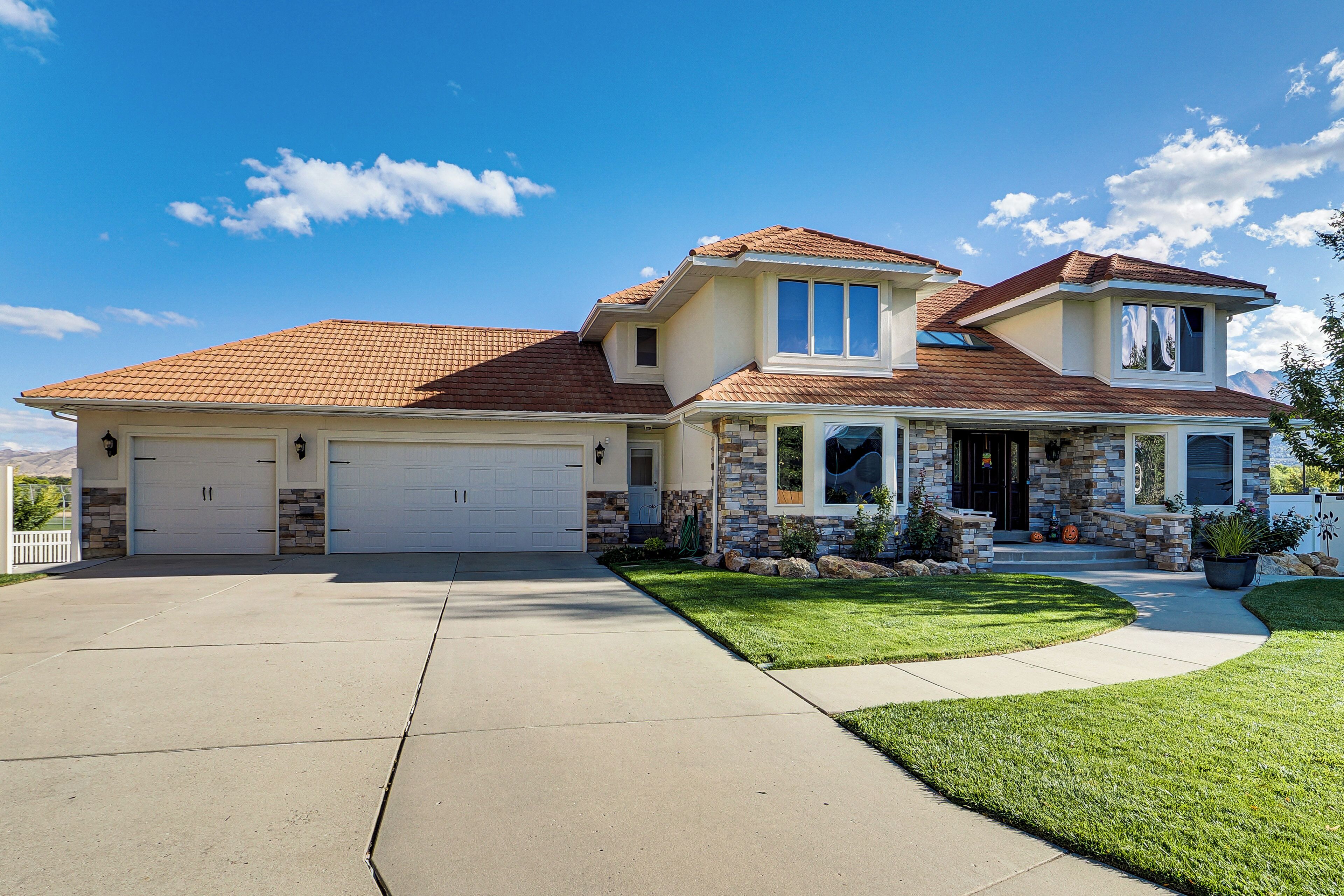 A two-story house with a garage, a covered porch, and a well-maintained lawn.