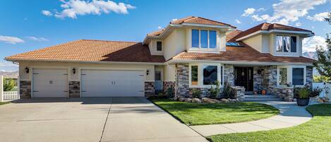 A two-story house with a garage, a covered porch, and a well-maintained lawn.