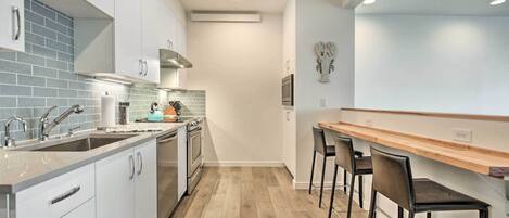 Una cocina moderna con armarios blancos, encimera de madera y horno empotrado.