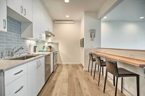 Une cuisine moderne avec des armoires blanches, un plan de travail en bois et un four encastré.