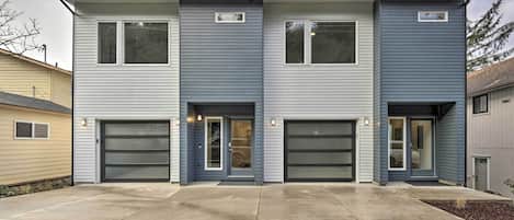 A modern two-story building with three garage doors and a concrete driveway.