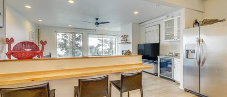 Una cocina moderna con una isla de madera, refrigerador de acero inoxidable y taburetes de bar.