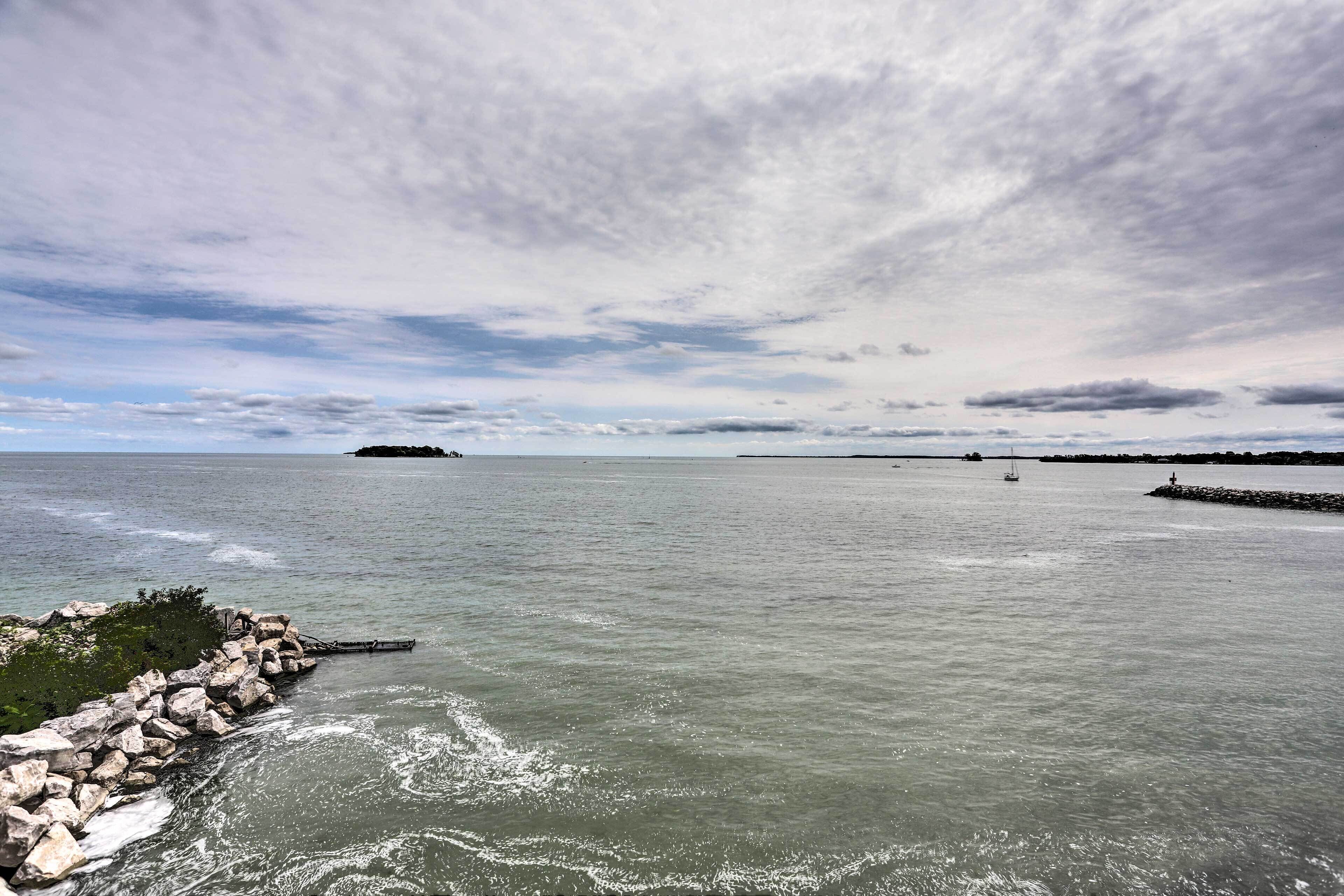 A coastal scene with a rocky breakwater, calm sea, and a distant island.