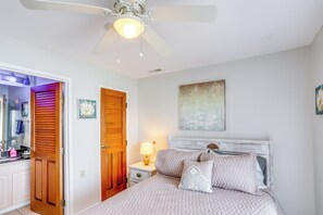 A bedroom with a bed, a nightstand, a ceiling fan, a wooden door, and a wall with a painting. - Cozy Lakefront Middle Bass Retreat w/ Balcony (Put-in-Bay)