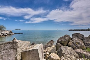 A rocky shoreline with calm water and a clear sky. - Cozy Lakefront Middle Bass Retreat w/ Balcony (Put-in-Bay)