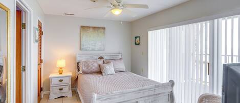 A bedroom with a bed, a nightstand, a ceiling fan, and a window with blinds.