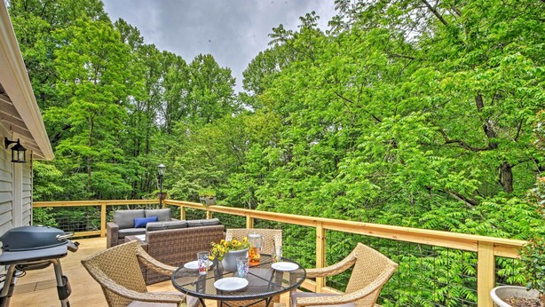 Eine Holzterrasse mit Korbmöbeln, einem Grill und einem Esstisch.