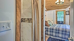 Ein Badezimmer mit Duschvorhang, Lichtschalter und Holzboden.