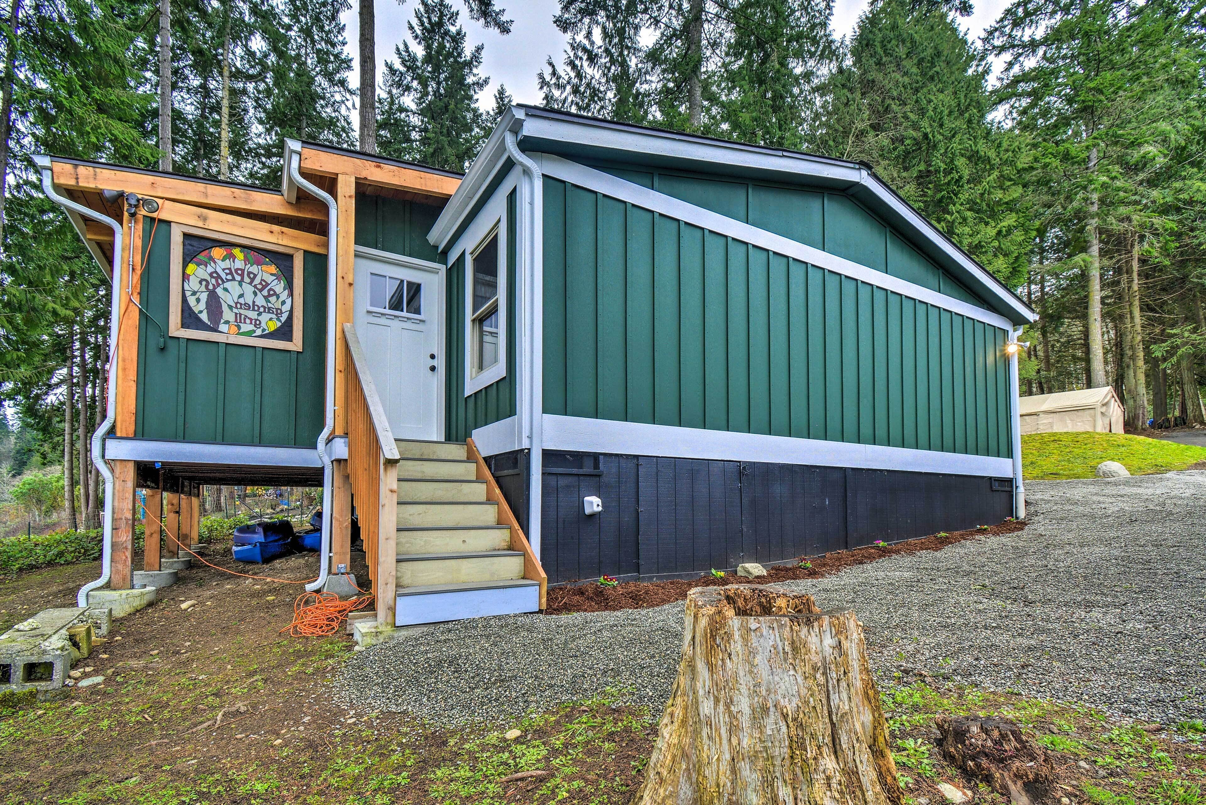 A small, single-story cabin with a green exterior and a wooden staircase leading to a door.