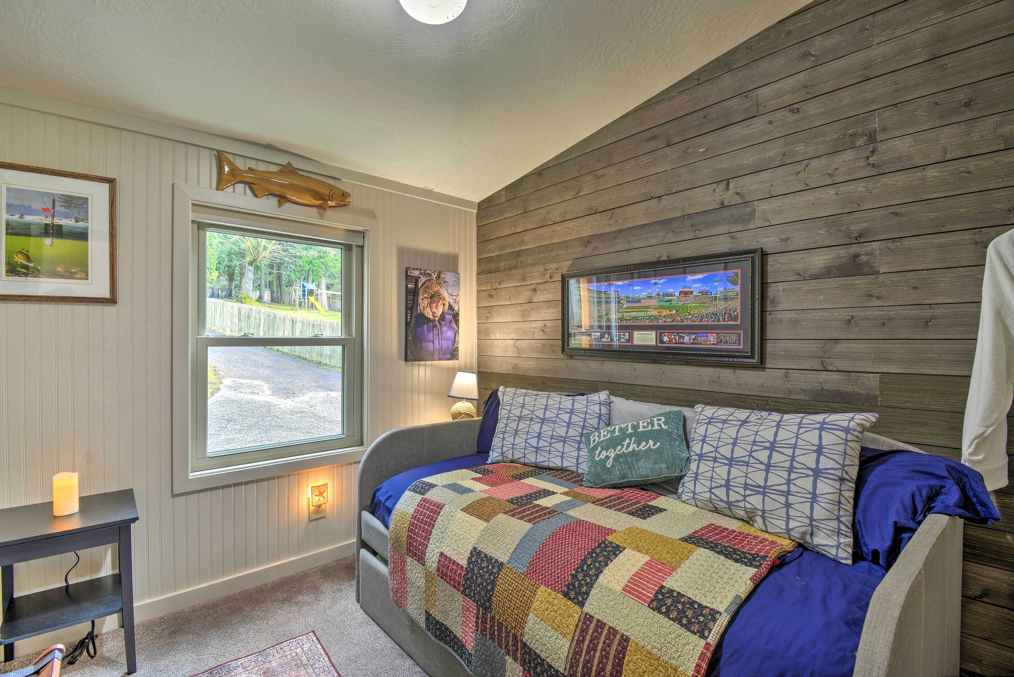 Una camera da letto con un letto, una finestra, un muro in legno e un quadro incorniciato.