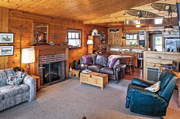 A cozy cabin interior with a fireplace, leather furniture, and wooden walls. - Newport Cabin w/ Lakefront Private Porch & Grill! (Newport)