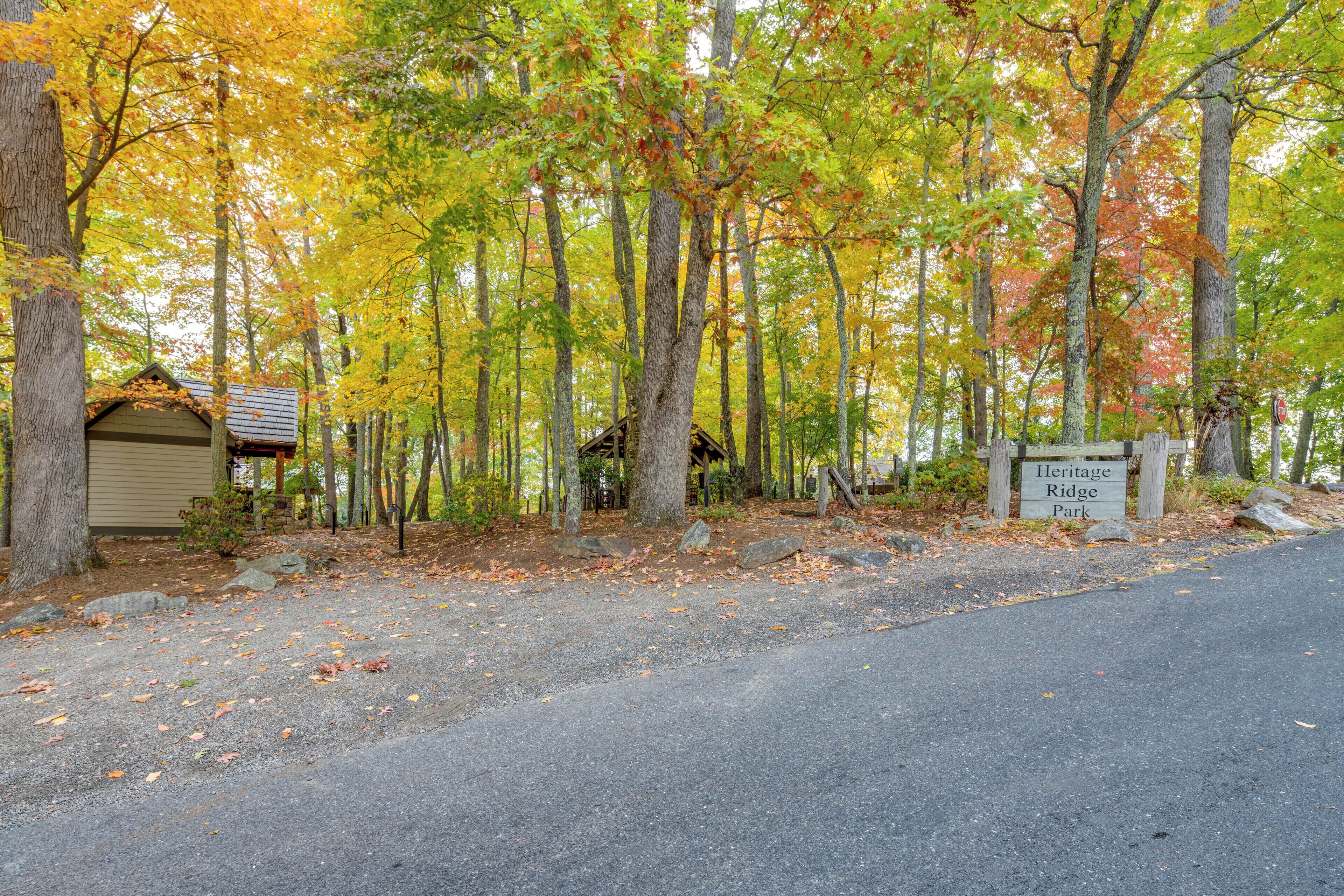 A paved driveway leading to a wooden cabin with a sign reading "Heritage Ridge Park".