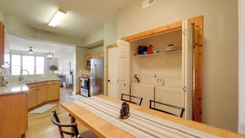A spacious kitchen with wooden cabinets, a dining table with chairs, and a refrigerator.