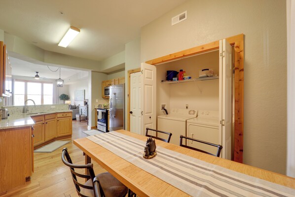 A spacious kitchen with wooden cabinets, a dining table with chairs, and a refrigerator.