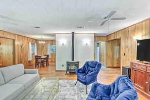 A spacious living room with a sofa, armchair, and a TV on a wooden cabinet. - Secluded Franklin Cabin w/ Furnished Deck! (Franklin)