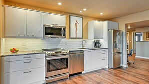 A modern kitchen with stainless steel appliances, white cabinetry, and a wooden floor. - Airy Home Near Anacortes w/ San Juan de Fuca Views (Anacortes)