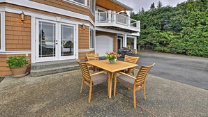 A two-story house with a balcony, a garage, and a patio with a table and chairs. - Airy Home Near Anacortes w/ San Juan de Fuca Views (Anacortes)