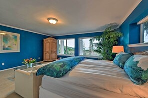 Un dormitorio con cama, mesita de noche, lámpara, ventana y vistas al exterior.