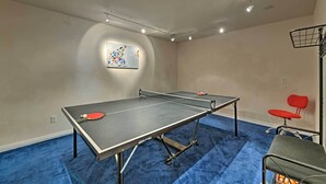 A ping pong table with two paddles, a red chair, and a small table with a basket. - Airy Home Near Anacortes w/ San Juan de Fuca Views (Anacortes)