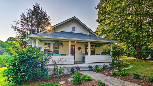 A single-story house with a porch, surrounded by a well-maintained garden and trees. - Restored Mars Hill Home on 1 Acre: Walk to Town! (Mars Hill)