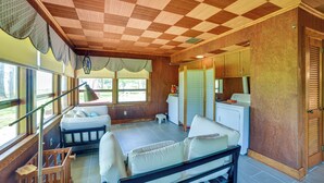 Ein Zimmer mit kariertem Himmel, einem Bett, einem kleinen Tisch und einem Fenster mit Vorhängen.