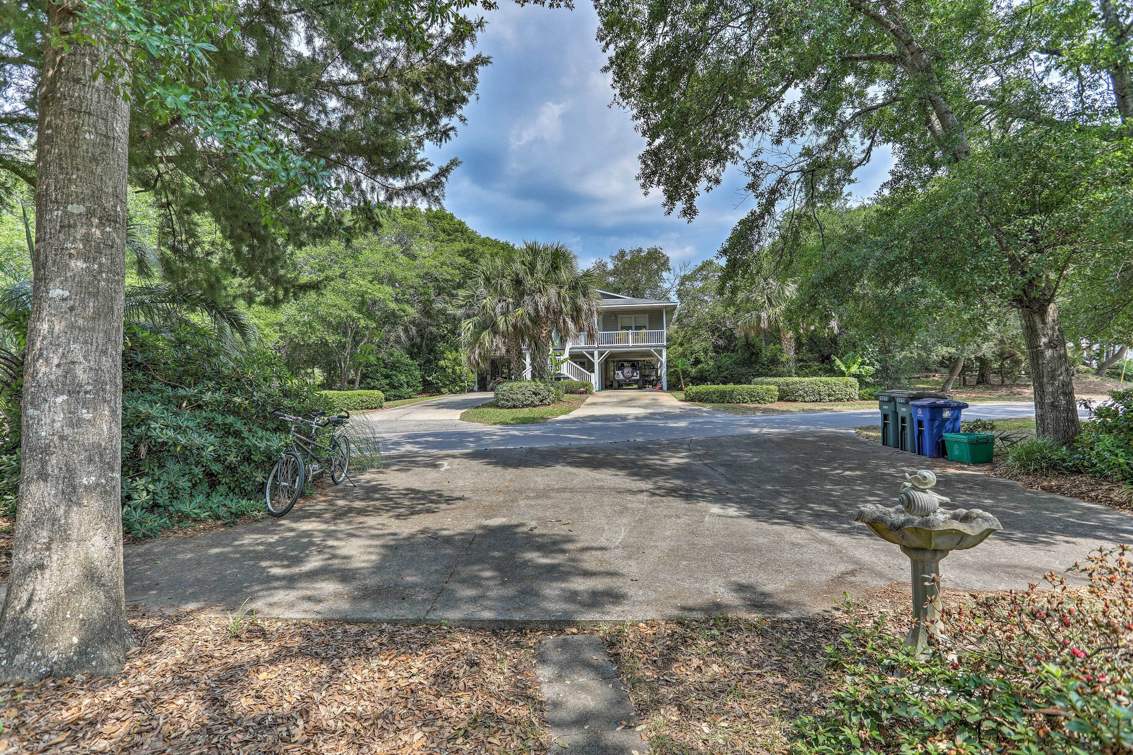 A residential property with a driveway leading to a house, surrounded by trees and a garden.