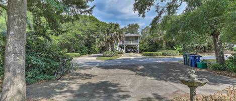 A residential property with a driveway leading to a house, surrounded by trees and a garden.