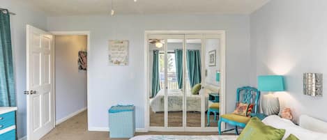 A bedroom with a bed, a ceiling fan, a wardrobe, a chair, a lamp, and a small rug.