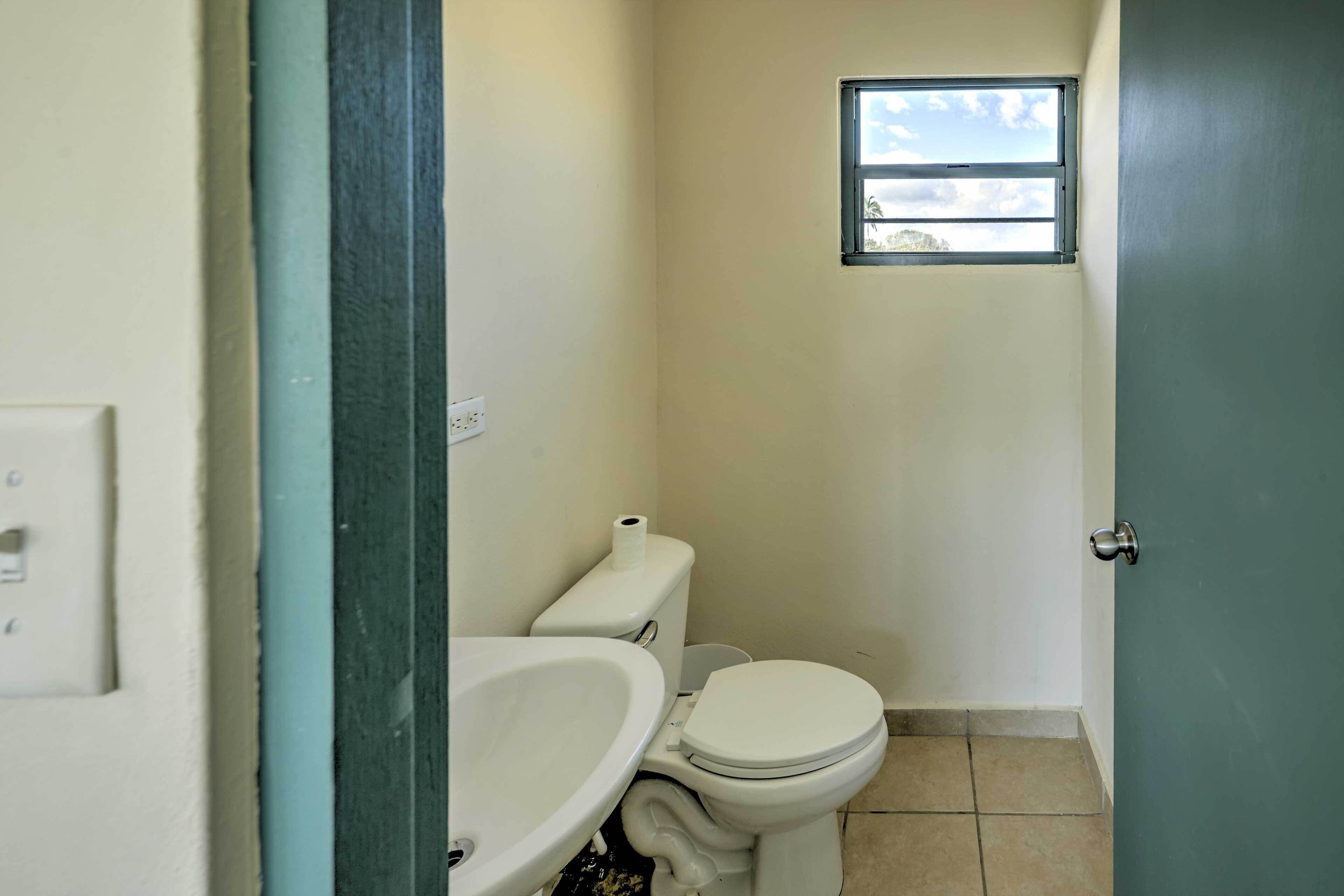 A small bathroom with a toilet, sink, and a window.
