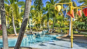 Ein Pool, umgeben von Palmen und ein Gebäude mit einer gefliesten Poolkante.