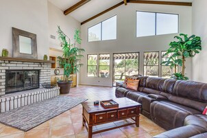 A living room with a fireplace, leather sofa, and large windows.