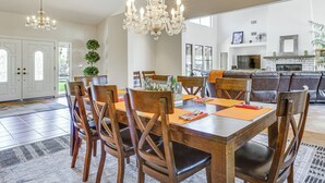 Un comedor amplio con una mesa y sillas de madera, un candelabro y vistas a la cocina.