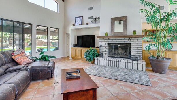 Amplia sala de estar con chimenea, sofá de cuero y ventanas grandes.