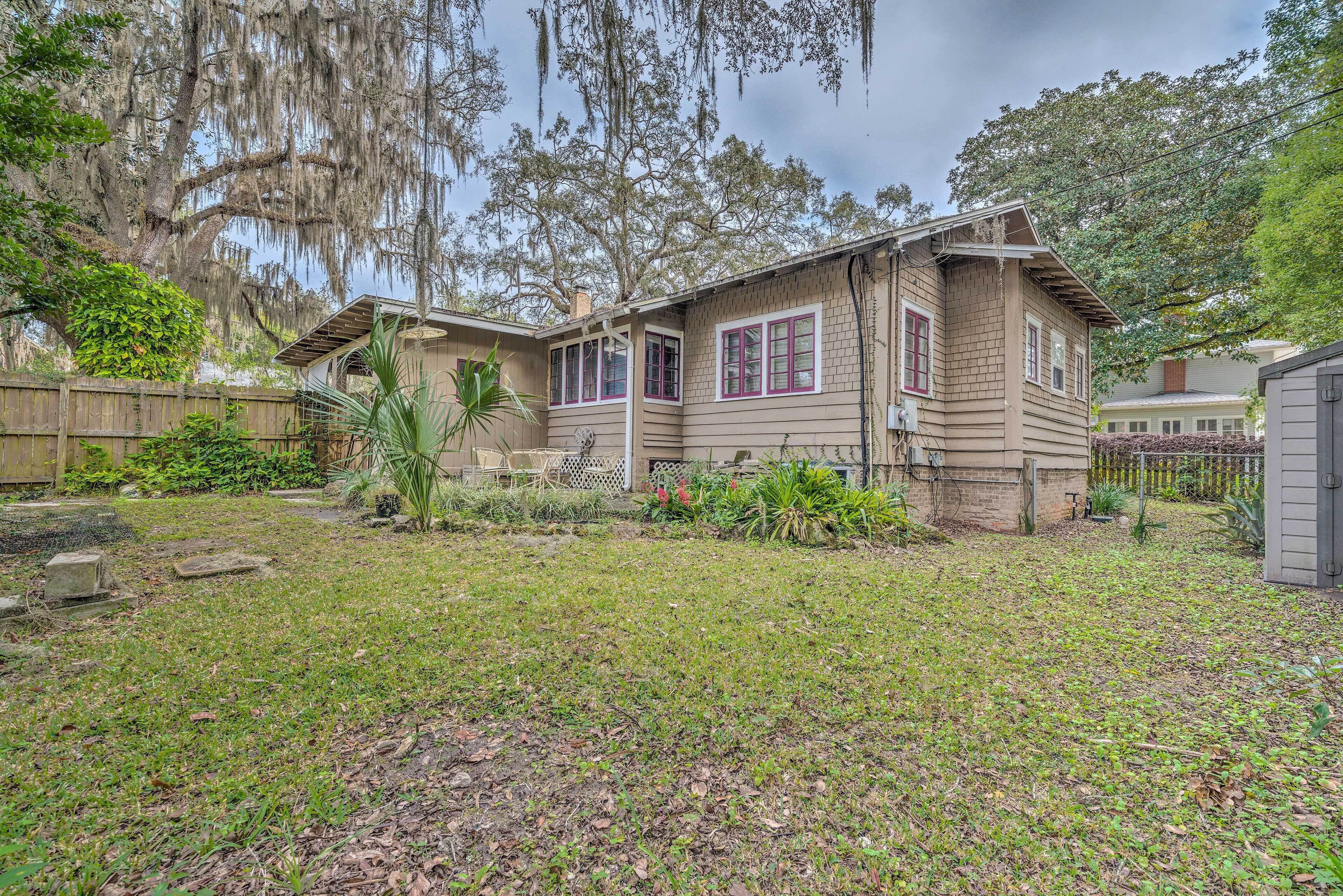 A two-story house with a front yard, a wooden fence, and a large tree with Spanish moss.
