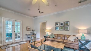 A spacious living room with a brown leather sofa, two wicker chairs, a wooden coffee table, and a glass side table with a lamp. - Chic Ocala Home w/ Yard ~ 1 Mi to Dtwn Square (Ocala)