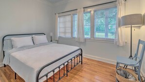 A bedroom with a bed, a chair, a lamp, and a window with curtains. - Chic Ocala Home w/ Yard ~ 1 Mi to Dtwn Square (Ocala)
