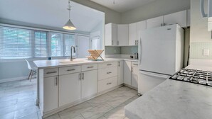 A modern kitchen with white cabinetry, a large refrigerator, and a gas stove. - Chic Ocala Home w/ Yard ~ 1 Mi to Dtwn Square (Ocala)