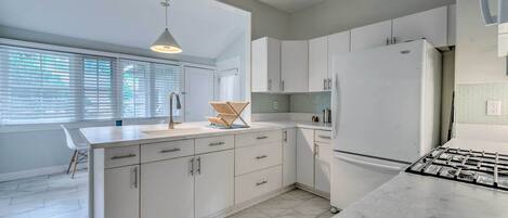 A modern kitchen with white cabinetry, a large refrigerator, and a gas stove.