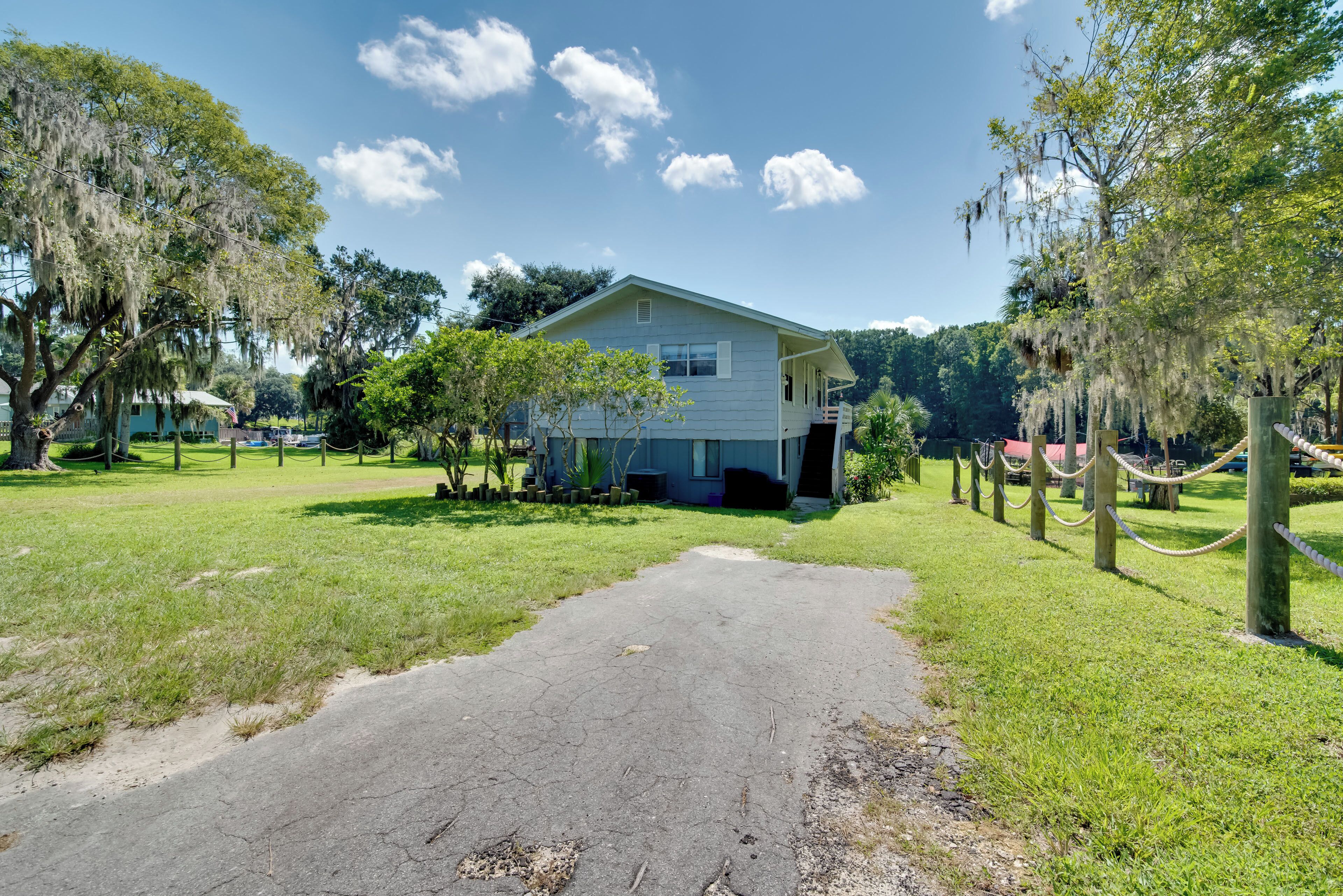 A two-story house with a front porch, surrounded by a grassy lawn and trees with Spanish moss.