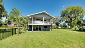 A two-story house with a balcony, surrounded by a well-maintained lawn and trees. - Docks + Balcony: Peaceful River Abode in Dunnellon (Dunnellon)
