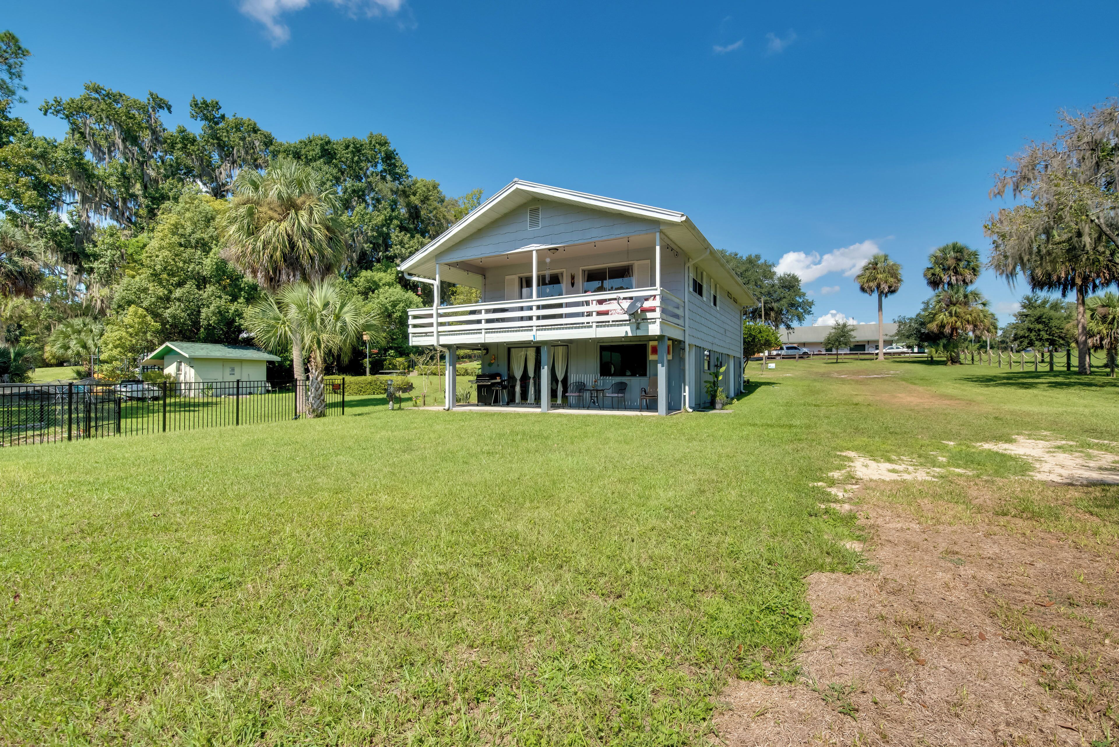 A two-story house with a balcony, surrounded by a well-maintained lawn and trees.