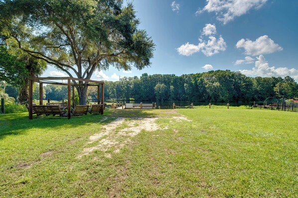 A gazebo with benches in a grassy park area with trees and a fence in the background. - Docks + Balcony: Peaceful River Abode in Dunnellon (Dunnellon)