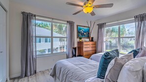 A bedroom with a bed, a dresser, a ceiling fan, and large windows. - Withlacoochee River House w/ Dock + Kayaks! (Inglis)