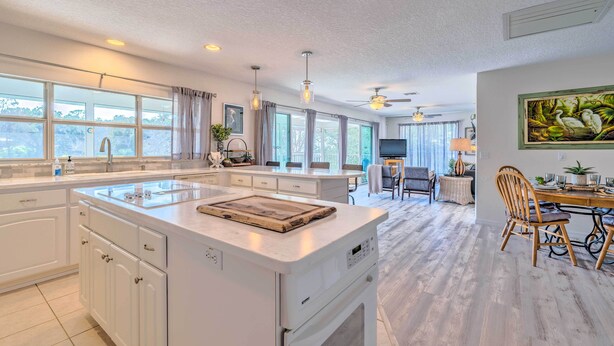 A spacious kitchen with a large island, white cabinetry, and a dining area with a wooden table and chairs. - Withlacoochee River House w/ Dock + Kayaks! (Inglis)