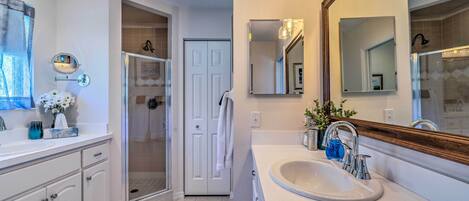 A bathroom with a white sink, a large mirror, and a shower area.