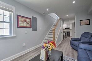 Un salon moderne avec un canapé bleu, un escalier et une cuisine en arrière-plan.