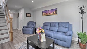 Ein Wohnzimmer mit einem blauen Sofa, einem Couchtisch mit Blumen in einer Vase und einem Gemälde vom Eiffelturm.
